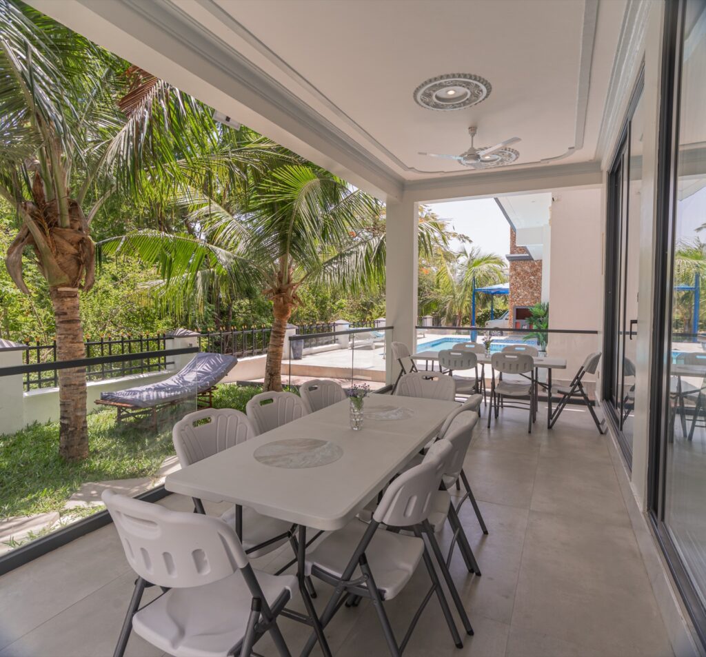 Covered outdoor dining terrace overlooking pool and palms